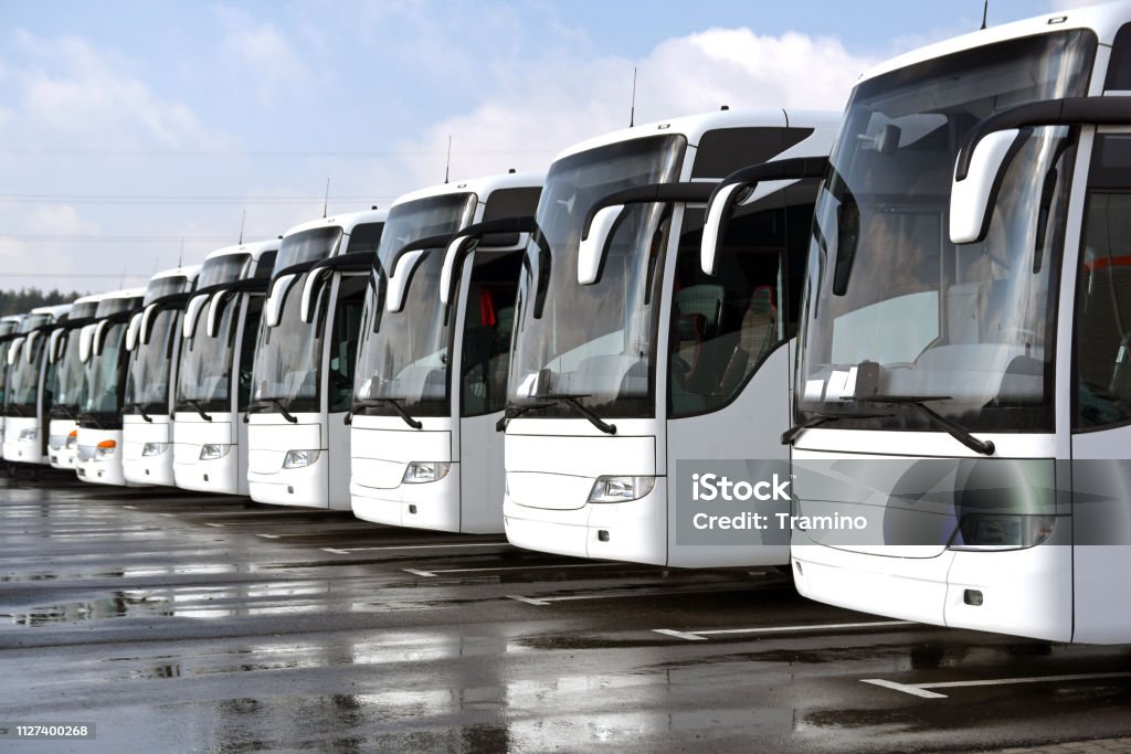 White coach buses in a row Front left side shot on the white tourist buses (coaches) in a row on the parking. Bus Stock Photo