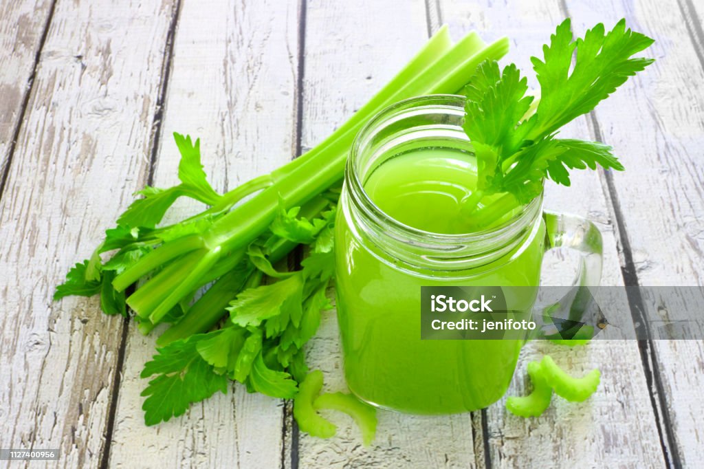 Celery juice in a mason jar against a white wood background Celery juice in a mason jar glass. Downward view over a rustic white wood background. Celery Stock Photo