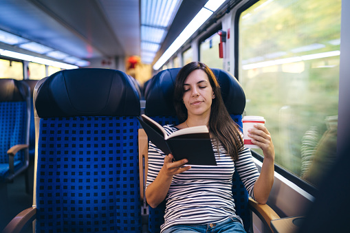 Young woman is reading a book in a train