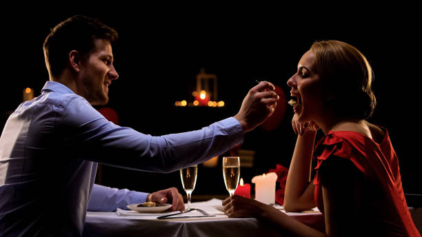 ハンサムな男がきれいな女性、レストランでロマンティックなディナーを持っているカップルを給餌 - aphrodisiac ストックフォトと画像
