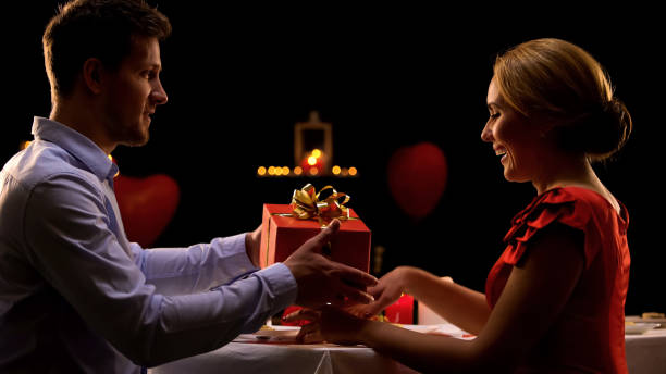 istock Handsome man giving red gift box to surprised seductive lady, be my valentine 1127406083