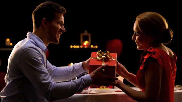 istock Man presenting lady red gift box, Valentines day surprise, romantic dinner 1127406085