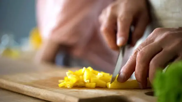 Chef cutting fresh pepper on kitchen board, culinary tips, salad ingredients