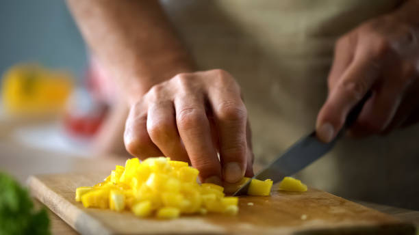 istock Mature husband cooking vegetable salad, cutting yellow pepper, culinary show 1127406228