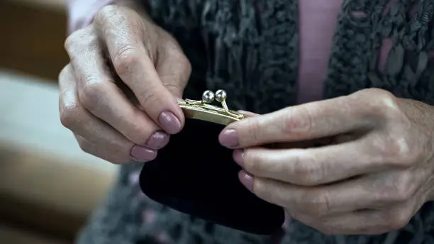 Old woman holding purse, social insecurity, lack of money, poverty, close-up