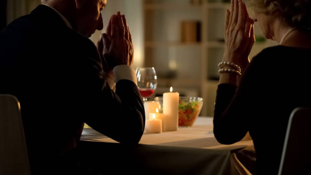 istock Old married couple praying before meal, sitting at table, Thanksgiving dinner 1127406728