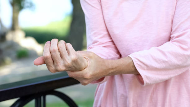 vecchia che allunga il braccio intorpidito, debolezza dei muscoli in età avanzata, artrite - debolezza foto e immagini stock