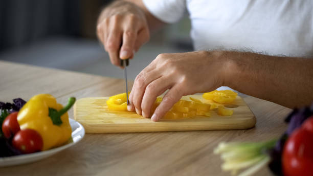 istock Husband cooking vegetarian lunch in kitchen, cutting yellow pepper on board 1127407736