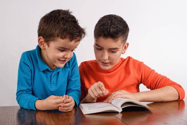 Hispanic brother and sister reading book together.