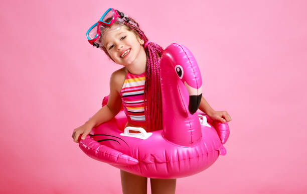 счастливая девочка в купальнике с плавательным кольцом фламинго на цветном розовом фоне - swimwear bikini swimming pool red стоковые фото и изображения
