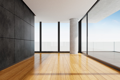 Modern and minimalist empty apartment with big panoramic windows and big terrace.
Black stone marble wall tiles. Bamboo tiles on the floor. Big concrete column. Terrace with big wooded tiles and glass fence.
Summer day scene. Copy space.