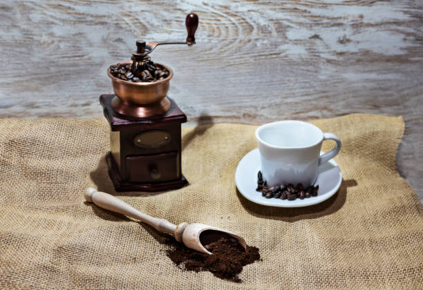 istock White cup and plate with beans, milling coffee and a wooden grinder on rustic background 1127422295