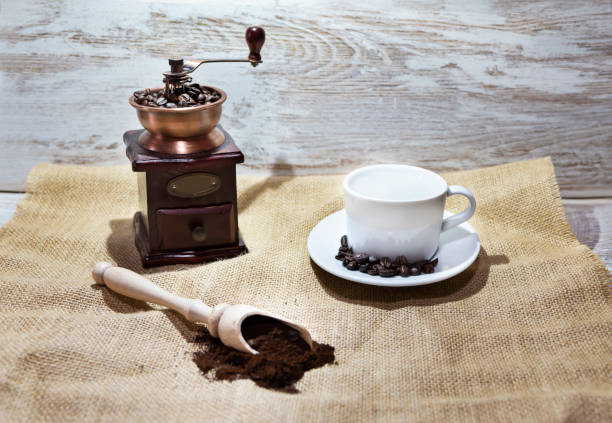 istock White cup and plate with beans, milling coffee and a wooden grinder on rustic background 1127422296