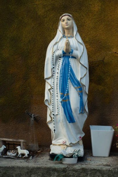 statua della vergine maria come simbolo di amore e gentilezza con offerte in piedi su una sporgenza di pietra contro una parete marrone - madonna della salute foto e immagini stock