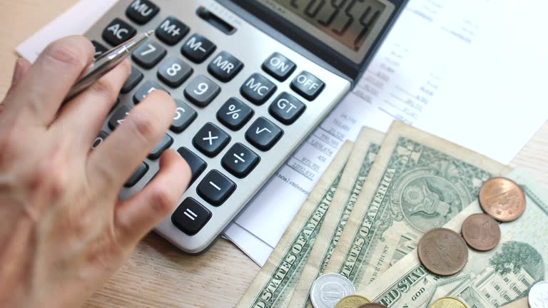 Woman Using Calculator For Taxes And Budget At Home