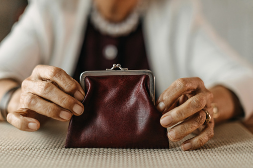 Old woman counting coins from her wallet