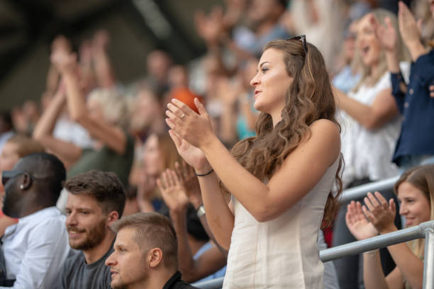 istock Young woman applauding while standing on stadium bleachers 1127427786