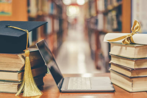 istock E-learning class and internet online education success with IT computer laptop, graduation hat, academic cap, mortarboard and degree certificate on books in class or library study room 1127431642
