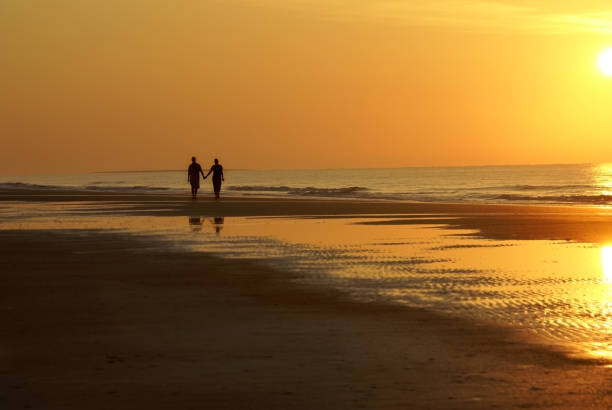 istock Couple Walking on Beach Silhouette 1127431655