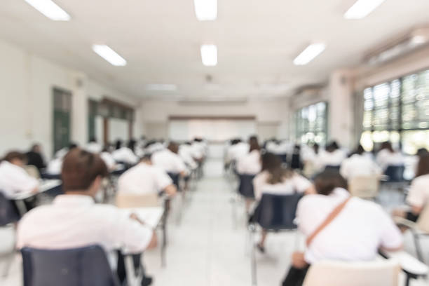 istock Blur school student exam background  in university class with blurry view from back of the classroom of young people having stress doing examination admission test in classroom for education 1127432589