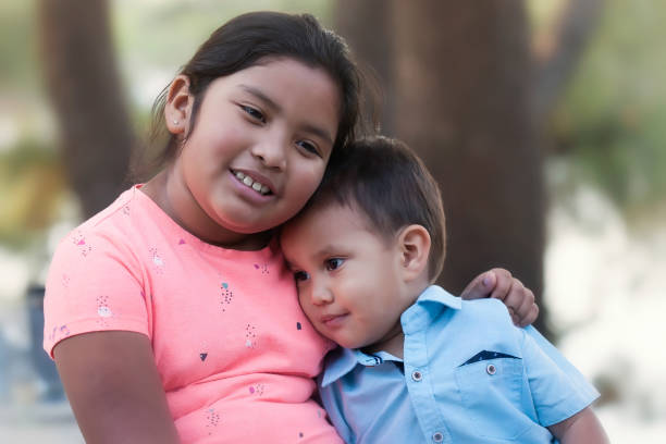 A young girl hugging a little boy and trying to encourage him while he looks upset, sad or depressed. stock photo
