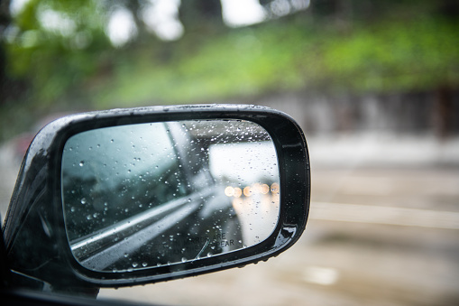 Photo through the passenger window of the side mirror on a wet gloomy day.