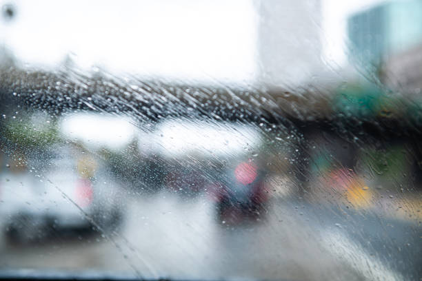 Windshield view of auto driving down residential street during rainy gloomy weather.
