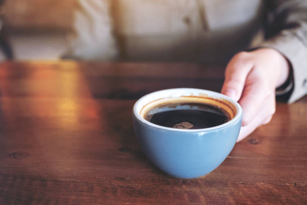 istock a hand holding a blue cup of hot black coffee 1127448274