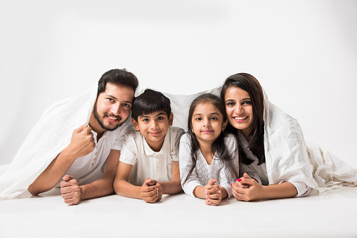 Indian parents with children lying under bed cover