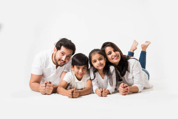 indyjska rodzina trzyma się za ręce pod brodą, leży na białej podłodze, selektywna ostrość - offspring family love india zdjęcia i obrazy z banku zdjęć