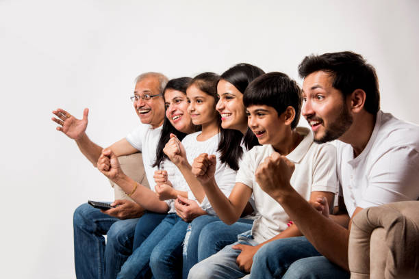 istock Multi generation Indian/asian family watching TV at home while sitting on sofa/couch, selective focus 1127456881