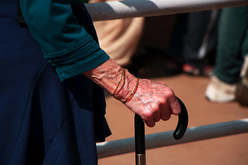 Mujer de edad avanzada caminando con la ayuda de un palo. Centrarse en la mano que sujeta un palo photo