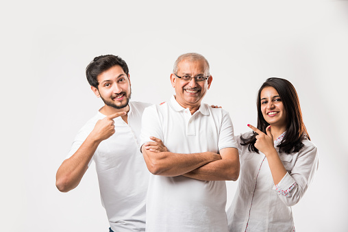 Indian old father embarrassing his young adult kids. Asian family of 3 standing isolated over white background. selective focus