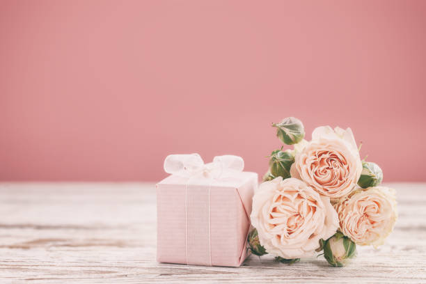 Pink roses flowers and gift or present box pink background. Mothers Day, Birthday, Valentines Day, Womens Day concept. stock photo