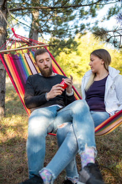 istock Young man and girl in orange hammock from back in beautiful forest 1127467476