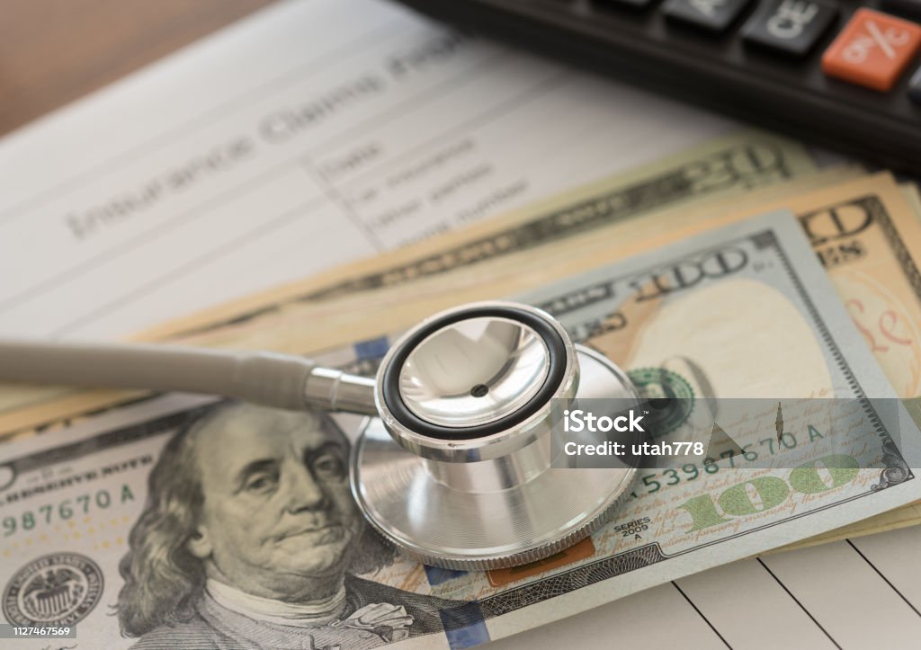 Health insurance claim Health insurance claim concept. Stethoscope on dollar banknote with calculator, health insurance claim form on desk. Healthcare And Medicine Stock Photo