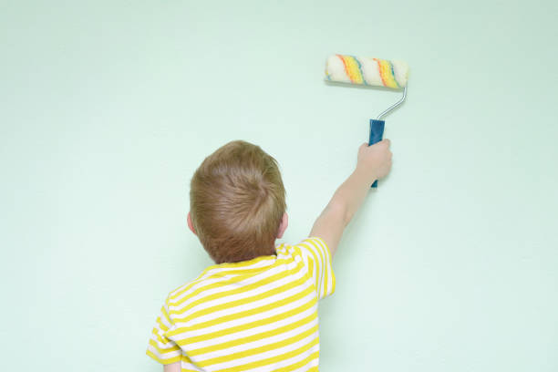 istock Boy paints the wall roller for painting. Back view 1127469367