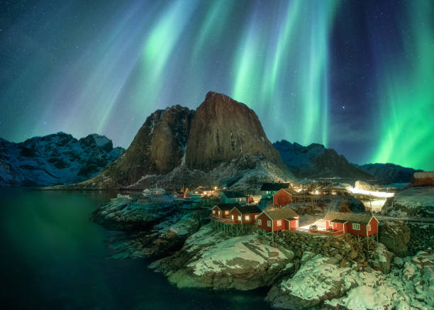 Northern lights over fishing village with mountain range on coastline at Hamnoy Northern lights over fishing village with mountain range on coastline at Hamnoy, Lofoten lofoten and vesteral islands photos stock pictures, royalty-free photos & images