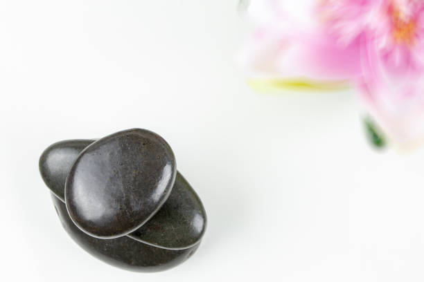 istock Stack of black pebbles on white background with flower 1127471557