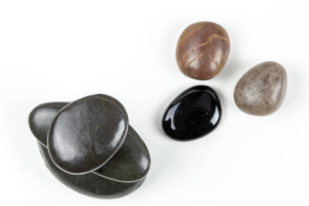 istock Black pebbles on white background with brown pebble. 1127471563