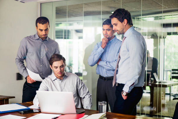 istock Male coworkers using laptop in board room 1127471644