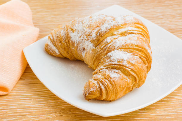 istock Croissant in powdered sugar on a white plate 1127472824