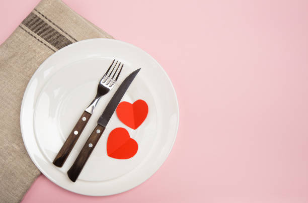 istock Festive table setting for Valentine's Day with fork, knife,  hearts on a red background. Top view. - Image 1127473382