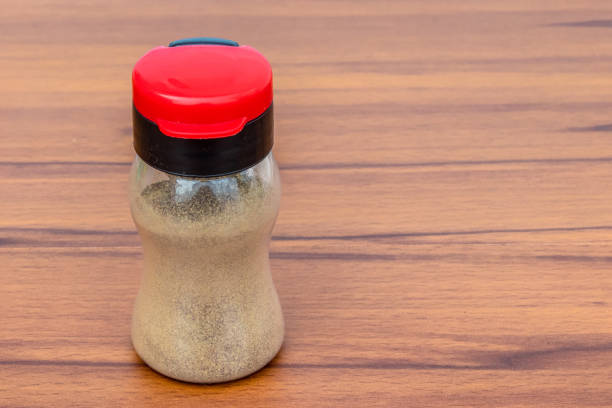 Black pepper shaker with colored cap Isolated on wooden Background