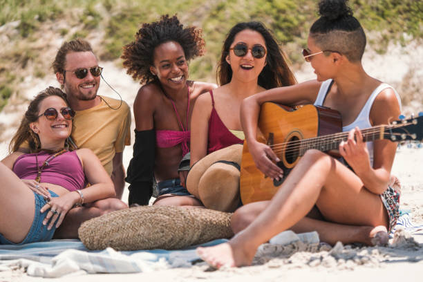 istock Woman playing guitar for friends at beach 1127476627