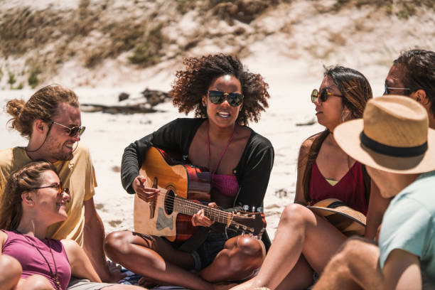 istock Woman playing guitar for friends at beach 1127477187