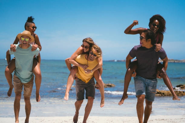 Young men piggybacking women at beach
