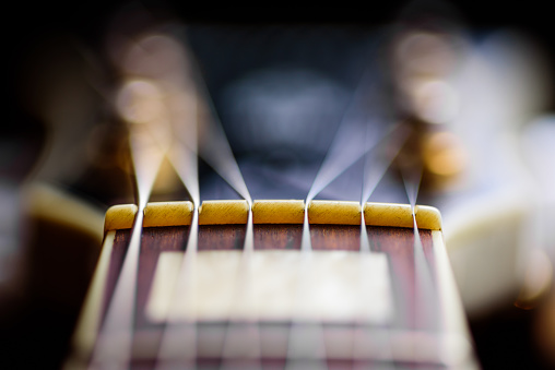 A very close view of an electric rock guitar fretboard and headstock