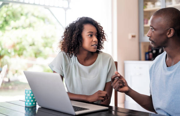 Serious young couple communicating at home Serious young couple communicating at home. Laptop is on table. Woman is looking at man while discussing in room. shaved black women stock pictures, royalty-free photos & images