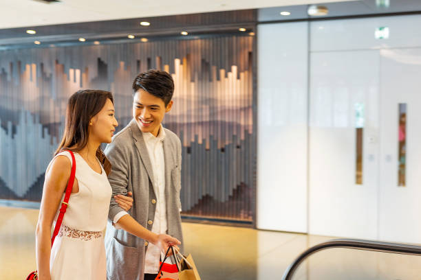 istock Asian Couple on an Escalator in a Shopping Mall 1127478459